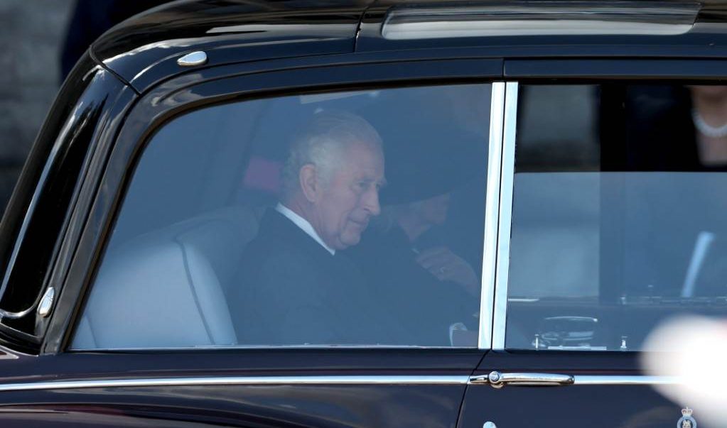 Britain’s King Charles III is pictured through Welsh flags as he arrives by car to visit Cardiff Castle, in south Wales on September 16, 2022. – King Charles III heads to Wales for the last of his visits to the four nations of the United Kingdom as preparations for the queen’s state funeral gather pace. (Photo by Adrian DENNIS / AFP)