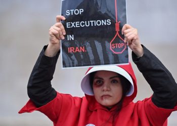 A protester wearing a ‘Handmaid’s Tale’ costume holds a placard during a silent march through central London on January 7, 2023, to raise awareness about the recent women-led uprising in Iran. (Photo by Justin TALLIS / AFP)