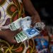 A vendor shows old and newly introduced Nigerian Naira banknotes in a market in Lagos on February 16, 2023. – Nigeria has been struggling with a shortage in physical cash since the Central Bank of Nigeria (CBN) began to swap old bills of the local naira currency for new, re-designed ones, leading to a shortfall in banknotes. (Photo by Michele Spatari / AFP)