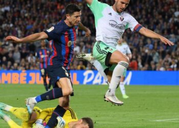 Osasuna’s Spanish goalkeeper Aitor Fernandez (BOTTOM) saves the ball as Barcelona’s Polish forward Robert Lewandowski (L) and Osasuna’s Spanish defender Unai Garcia jump over him during the Spanish league football match between FC Barcelona and CA Osasuna at the Camp Nou stadium in Barcelona on May 2, 2023. (Photo by LLUIS GENE / AFP)