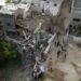 In this aerial view, people gather in front of a building hit by an Israeli air strike, in Gaza city on May 13, 2023. – Israel and Gaza traded heavy fire on May 12 but Egyptian mediators launched a new bid to end days of fighting that has killed dozens, all but one of them Palestinian. (Photo by MAHMUD HAMS / AFP)