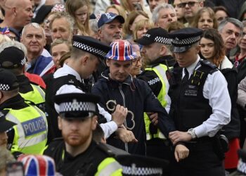 Protesters from climate protest group 'Just Stop Oil' are apprehended by police officers in the crowd close to where Britain's King Charles III and Britain's Camilla, Queen Consort will be crowned at Westminster Abbey in central London on May 6, 2023. - The set-piece coronation is the first in Britain in 70 years, and only the second in history to be televised. Charles will be the 40th reigning monarch to be crowned at the central London church since King William I in 1066. (Photo by JUSTIN TALLIS / POOL / AFP)