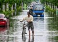 A man pushes a bicycle down a road closed due to flooding at Koshigaya, Saitama Prefecture on June 3, 2023, after heavy rains caused by passing Tropical Storm Mawar hit much of the country the day before. – Heavy rain across parts of Japan has killed one person, left two missing and injured dozens more, authorities said on June 2, with thousands of residents issued evacuation warnings. (Photo by STR / JIJI Press / AFP) / Japan OUT / JAPAN OUT