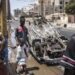 People walk past a burned out car in Dakar, on June 5, 2023, as protest calmed down four days after a court in Senegal sentenced opposition leader Ousmane Sonko, a candidate in the 2024 presidential election, to two years in prison on charges of “corrupting youth” but acquitted him of rape and issuing death threats. (Photo by JOHN WESSELS / AFP)
