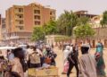 Pedestrians and vehicles move along a road outside a branch of the Central Bank of Sudan in the country’s eastern city of Gedaref on July 9, 2023. – Many civil servants in Sudan have been going on without a salary since the Sudanese army and the paramilitary Rapid Support Forces took up arms against each other. (Photo by – / AFP)