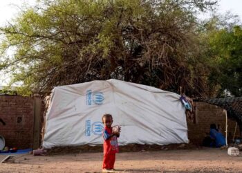An internally displaced child stands outside a tent pitched at the Hasahisa secondary school on July 10, 2023, which has been made into a make-shift camp to house those fleeing violence in war-torn Sudan. – Conflict-torn Sudan is on the brink of a “full-scale civil war” that could destabilise the entire region, the United Nations warned on July 9, after an air strike on a residential area killed around two dozen civilians. (Photo by – / AFP)