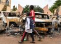Children walk past burned cars outside the headquarters of president Bazoum’s Nigerien Party for Democracy and Socialism in Niamey on August 7, 2023. – Niger’s military rulers were on Monday in defiance of an ultimatum to restore the elected government as the threat of possible military intervention was still on the table. (Photo by – / AFP)