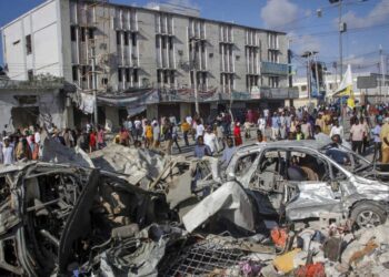 People walk amidst destruction at the scene, a day after a double car bomb attack at a busy junction in Mogadishu, Somalia Sunday, Oct. 30, 2022. Somalia’s president says multiple people were killed in Saturday’s attacks and the toll could rise in the country’s deadliest attack since a truck bombing at the same spot five years ago killed more than 500. (AP Photo/Farah Abdi Warsameh)