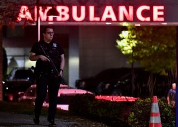 An armed police officer guards the ambulance entrance to the Central Maine Medical Center in Lewiston, Maine early on October 26, 2023. – A massive manhunt was under way on October 26 for a gunman who a local official said killed at least 22 people and wounded dozens more in mass shootings in the US state of Maine, the deadliest such incident this year. (Photo by Joseph Prezioso / AFP)