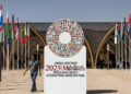 A man walks past the emblem of the 2023 IMF and World Bank annual meetings situated at the entrance of the venue in Marrakesh on October 8, 2023. (Photo by FADEL SENNA / AFP)