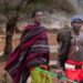 Lisoka Lesasuyan (L), 21, is led by his brother, Joshua as they walk along a dirt road after contact with a piece of unexploded military ordnance in 2013 left Lisoka a double-amputee whose lost both his arms, partially blind and deaf, at Kipsing village, Isiolo county on October 18, 2023. (Photo by Tony KARUMBA / AFP)