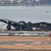 Officials look at the burnt wreckage of a Japan Airlines (JAL) passenger plane on the tarmac at Tokyo International Airport at Haneda in Tokyo on January 3, 2024, the morning after the JAL airliner hit a smaller coast guard plane on the ground. – Five people aboard a Japan coast guard aircraft died on January 2 when it hit a Japan Airlines passenger plane on the ground in a fiery collision at Tokyo’s Haneda airport. (Photo by Richard A. Brooks / AFP)